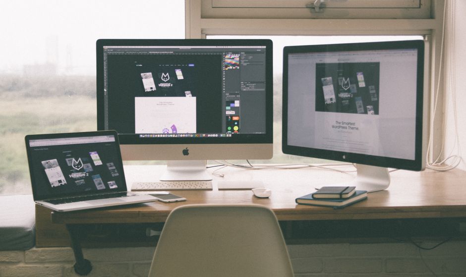 Espaço de trabalho elegante e eficiente com múltiplos monitores, laptop e smartphone, exibindo um projeto de design de w